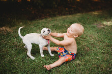 Happy Baby Laughing With A Beautiful Puppy Outside In Summer