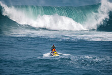 Rescue Lifeguard In The Ocean In Front Of A Big Wave On A Jet Ski Searching For Surfers