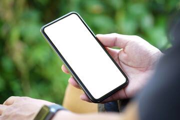 Wall Mural - mock up image of young man sitting in the park and holding smart phone with bank screen for advertis