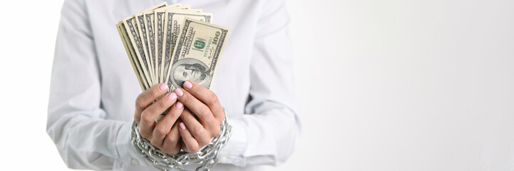 Women hands tied with chain hold one hundred dollar bills