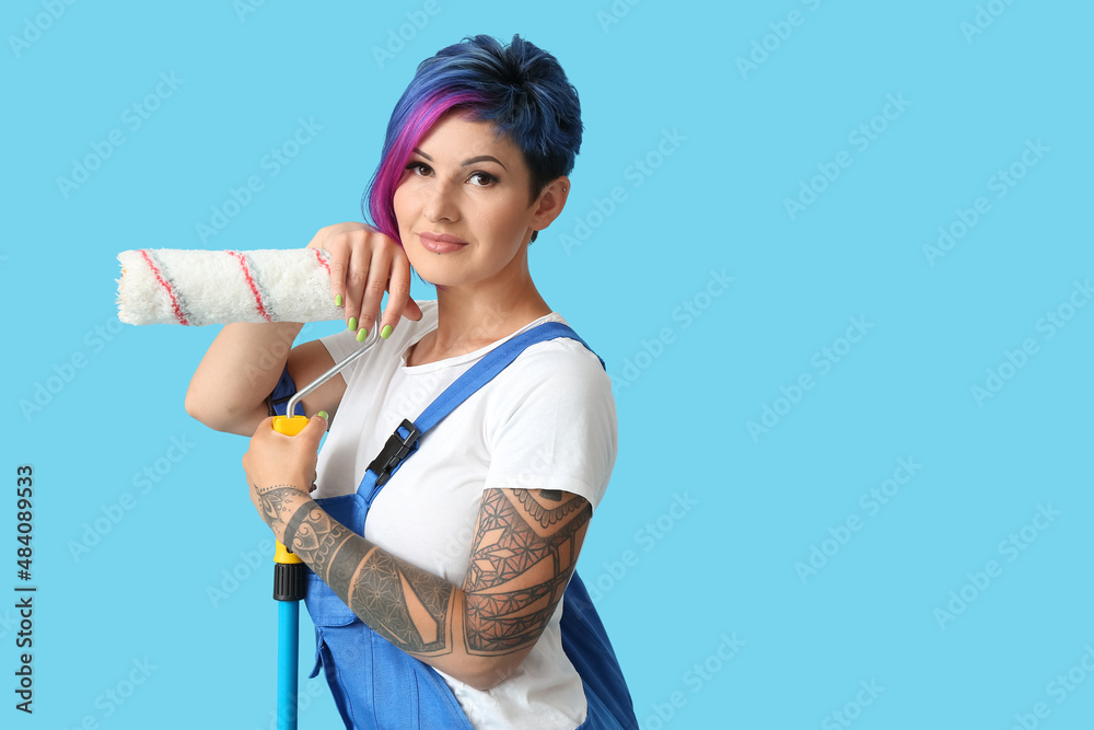 Female painter with bright hair and paint roller on blue background