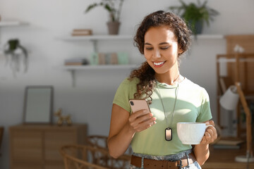 Wall Mural - African-American female soldier with mobile phone and tea at home