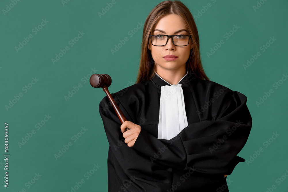 Young female judge with gavel on color background