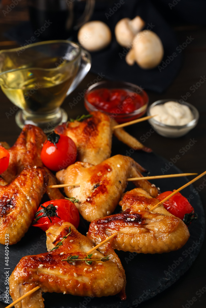 Board with grilled chicken wings skewers and vegetables on table