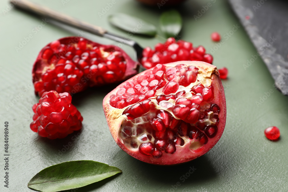 Ripe delicious pomegranate on green wooden background