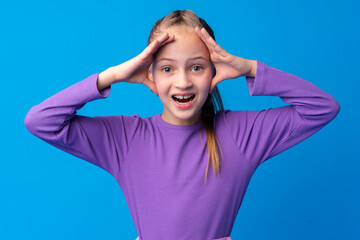 Shocked little girl looking with amazement on blue background