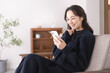 © lielos - リビングのソファー座り携帯電話を見ている日本人女性