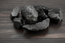 Black Rock Stone Or Bituminous Coal Or Slate On Wooden Floor