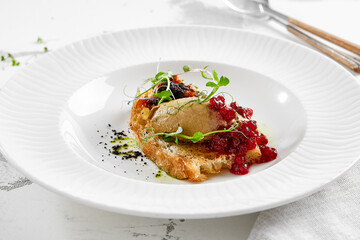 Chicken liver pate on crispy bread with red currant jam and micro green. Bruschetta with chicken pate in white plate. Delicious appetizer - foie gras on toast. Liver pate with jam in rustic style.