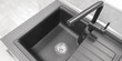 Close-up top view integrated single basin bowl sink with drainboard, dark color. Wing for drying utencil with grooves for draining water. Mixer tap of same material, neutral light kitchen background.