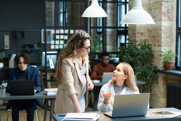 Poster - Young businesswoman explaining something to pregnant colleague during discussion of workng points against male coworkers