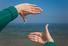 Close-up Point Of View Shot Photography Of Female Caucasian Hands Isolated On Blue Sky Background. Young Woman Forming Frame With Her Two Hands As If Looking At Something Virtual And Invisible