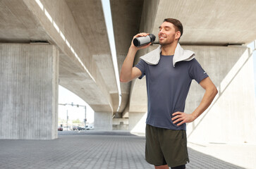 Sticker - fitness, sport and healthy lifestyle concept - smiling man in sports clothes with towel on his neck drinking from bottle under bridge on background