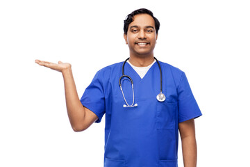 Sticker - healthcare, profession and medicine concept - happy smiling indian doctor or male nurse in blue uniform holding something imaginary on empty hand over white background