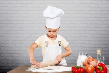 Sticker - Toddler child playing with the dough in the kitchen dressed as a chef. Child baking a cake