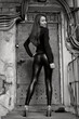 Young beautiful female model standing before the old rusty door. Elegant leggings. Black and white photo