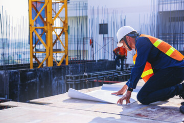 Wall Mural - Structural engineer or foreman worker with blueprints inspecting for the outdoors building construction site.	