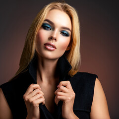 Wall Mural - Photo of young stylish  woman in black clothes with  blue make-up. Portrait of sexy blonde woman with a beautiful face. Fashion model with long hair, studio shot.