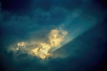 Wall Mural - a photo of golden rays of light on the dark blue sky forming a yellow heart shape among the clouds