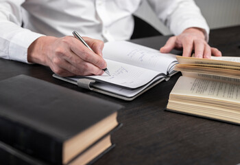 Poster - Man hands taking notes in planner. Businessman sitting at table with books or codes at home or in office and writing thesis or thoughts. Learning and business education concept. High quality photo