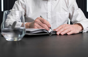 Poster - Man hands taking notes in planner. Employee sitting at desk and writing plans. Business planning concept. . High quality photo