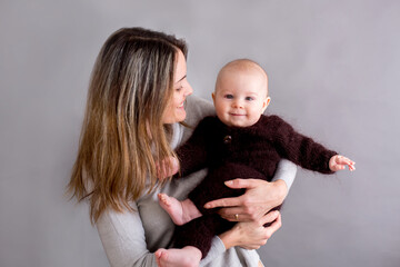 Sticker - Young mother, caressing her newborn baby boy, holding him in her arms and smiling