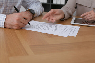 Poster - Businesspeople signing contract at wooden table, closeup of hands