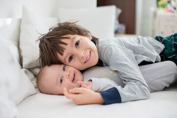 Canvas Print - Two children, baby and his older brother in bed in the morning, playing together