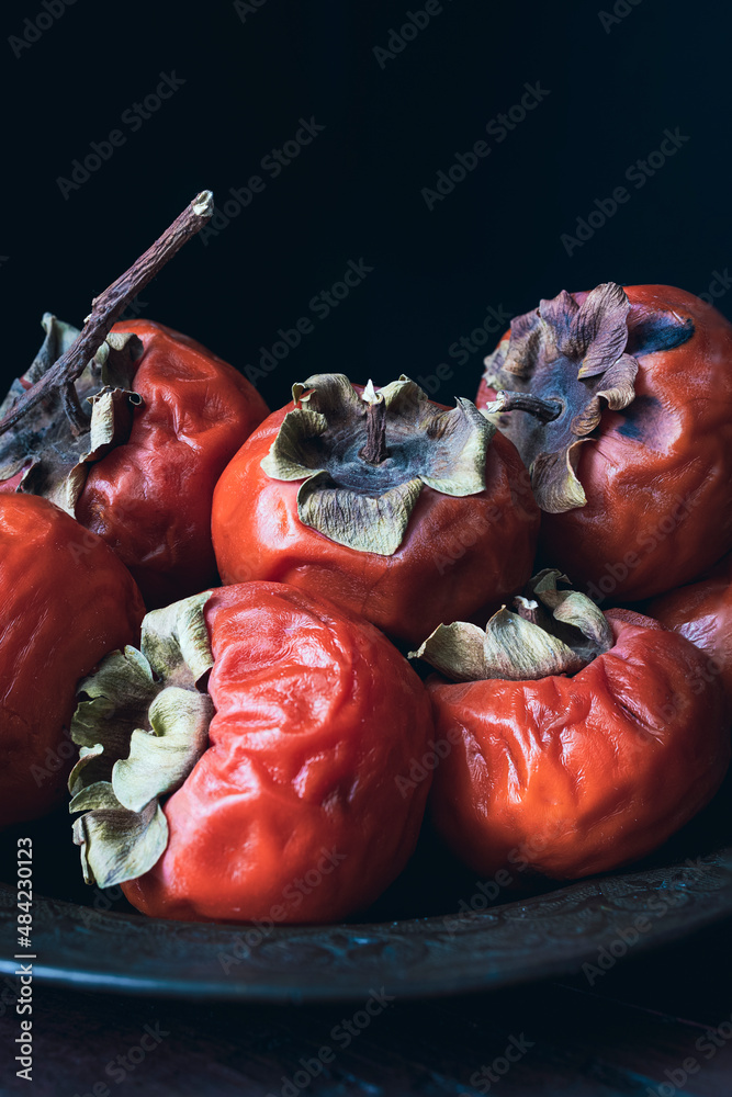 Dish with overripe persimmons. Concept of wrinkled skin, passage of ...
