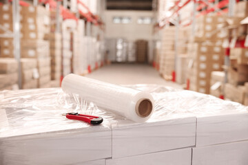 Poster - Roll of stretch wrap and utility knife on boxes in warehouse