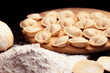 © EllSan - Raw meat dumplings and flour on dark background close-up. Traditional Russian pelmeni. Selective focus.