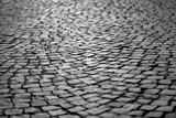 Fototapeta  - Cobblestone street in Iserlohn Sauerland Germany. Wheathered historic basalt ashlars or blocks in a lost place industrial area. Old pavement background with typical surface and structure, greyscale.