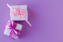 Two Gift Boxes With Pink And Purple White Polka Dot Ribbon Bows On Purple Background