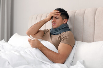 Sticker - Sick man with scarf and tissue suffering from cold in bed at home