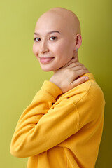 Portrait of young caucasian bald lady isolated on green studio background. Beautiful female model in yellow casual shirt, laughing. Human emotions, facial expression, sales, ad. Freaky culture.