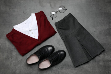 Wall Mural - Stylish school uniform for girl and glasses on grey background, flat lay