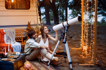 a young couple travels in a camper. enjoy each other watching the starry sky through a telescope. rest in a caravan. love in motorhomes