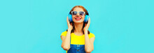 Portrait Of Happy Smiling Woman Listening To Music In Headphones On Colorful Blue Background