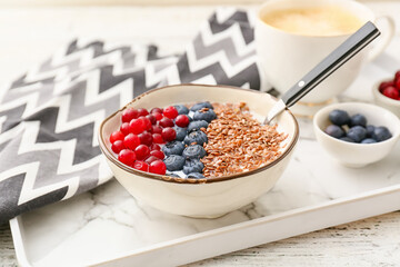 Tray with bowl of sweet yogurt with flax seeds and berries on table