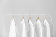 © Pixel-Shot - Rack with clean shirts in plastic bags on grey background
