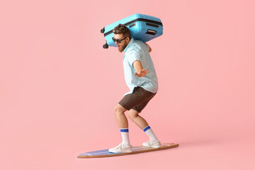 Wall Mural - Handsome man with surfboard and suitcase on pink background