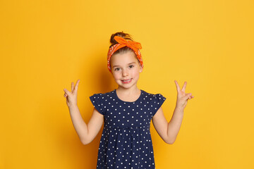 cute little girl wearing stylish bandana on orange background