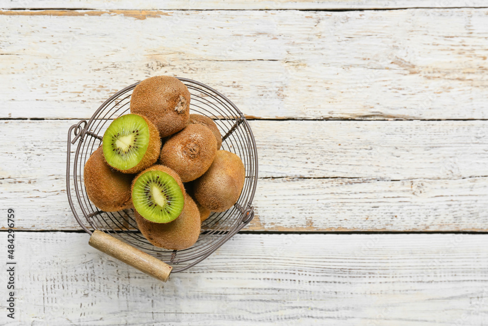 Basket with fresh ripe kiwi on light wooden background