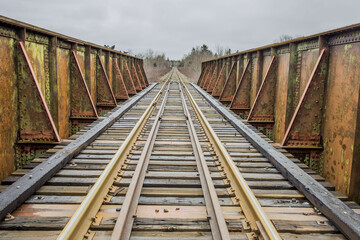 Sticker - A long, wooden train railways on a cloudy sky