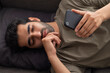 © IndiaPix - Portrait of a young man lying on sofa and looking at the Smartphone