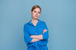 Photo an attractive business woman with looking at camera, responsible person, arms crossed, wearing a casual blue shirt, caucasian girl posing, isolated on a blue colored background