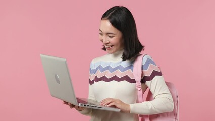 Wall Mural - Girl teen student of Asian ethnicity wear shirt backpack hold use type work on laptop pc computer isolated plain pastel light pink background studio portrait. Education in university college concept