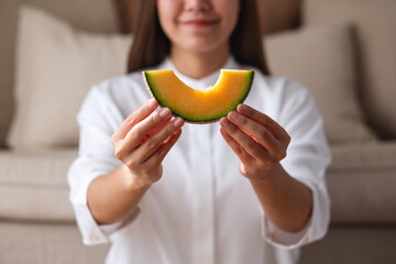 Wall Mural - Closeup image of a young woman holding and showing a piece of Cantaloupe melon