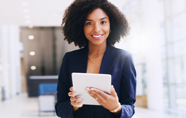 Wall Mural - Updating my work schedule. Cropped portrait of an attractive young businesswoman standing alone and using a tablet while in the office during the day.