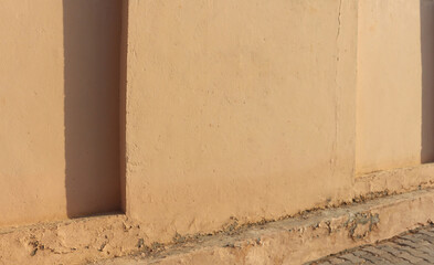 An old plastered cracked wall with summer abstract shadows and light on it. Grunge rough background.